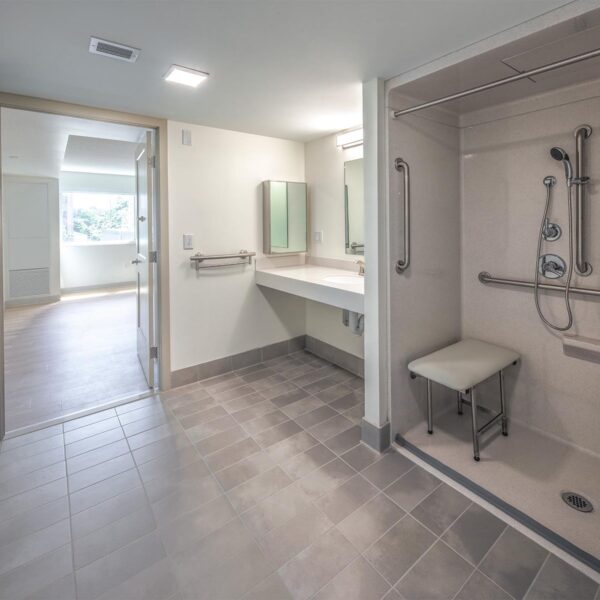 bathroom with roll-in shower with bench seat and wheelchair accessible sink
