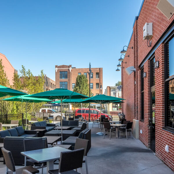 Patio outside of brick building with tables, chairs and umbrellas
