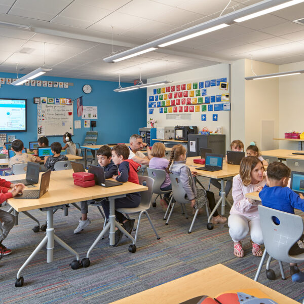 Elementary students and teacher using laptops in classroom