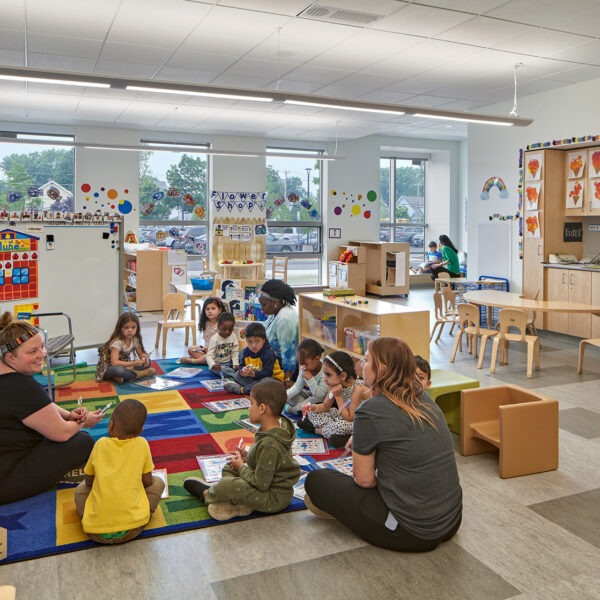 preschool children and teachers sitting on colorful carpet in classroom