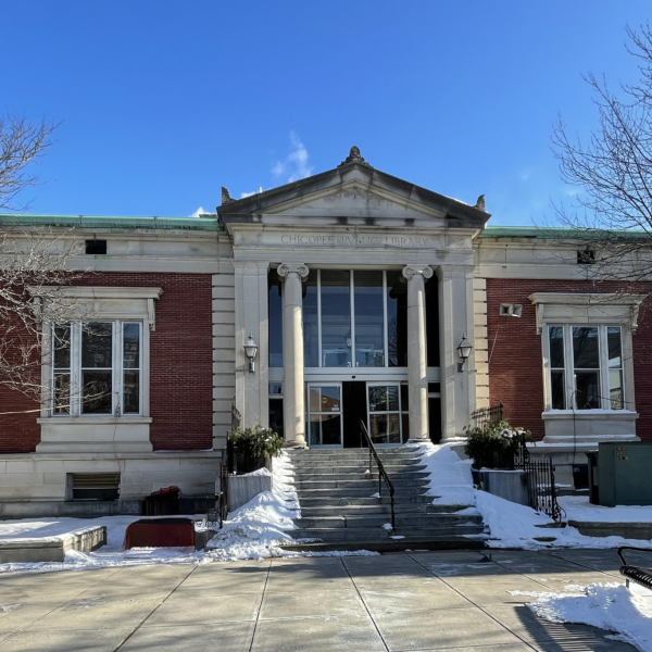 Former Chicopee Public Library building with red brick and beige stone facade, large glass entrance, and snow-covered steps.