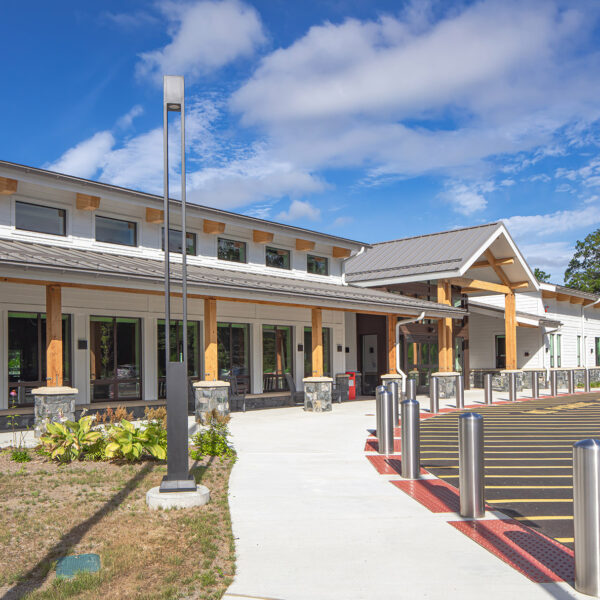 Modern building exterior with large windows and wooden beams under a blue sky.